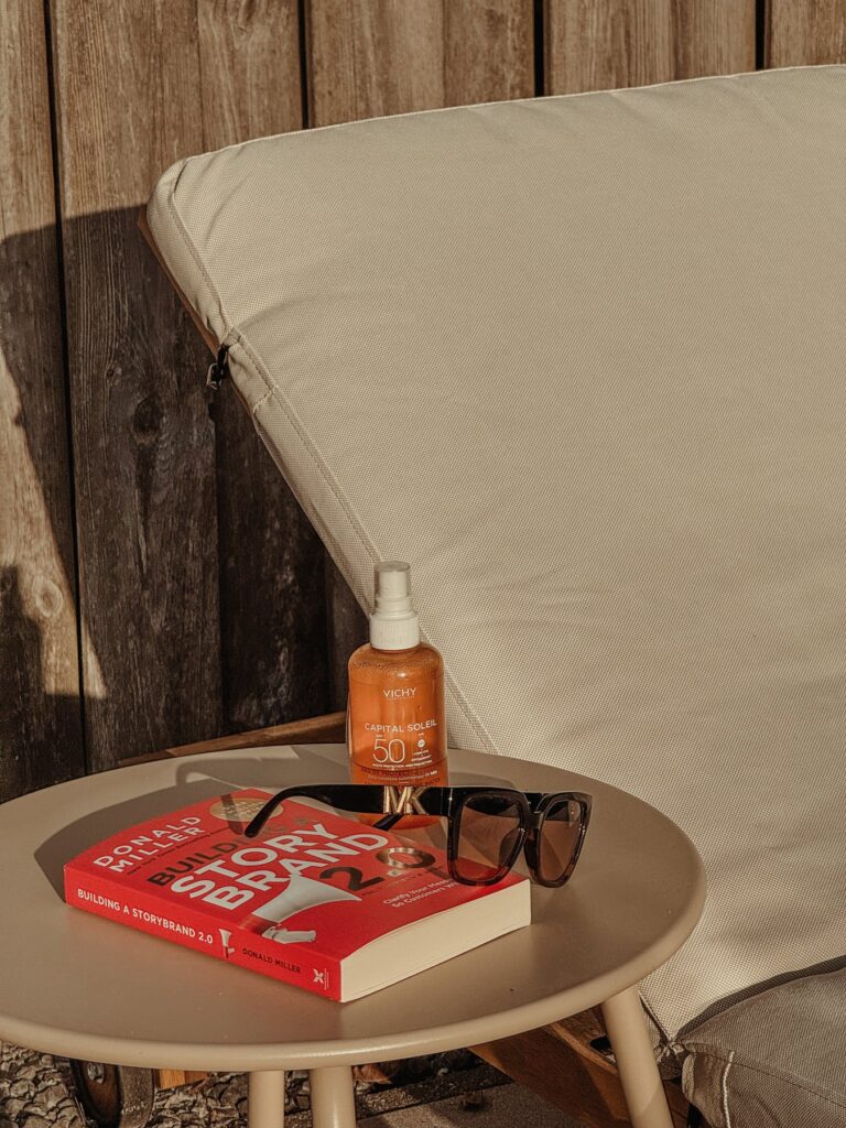 Ligbed met bijzettafel, boek, zonnebril en zonnespray