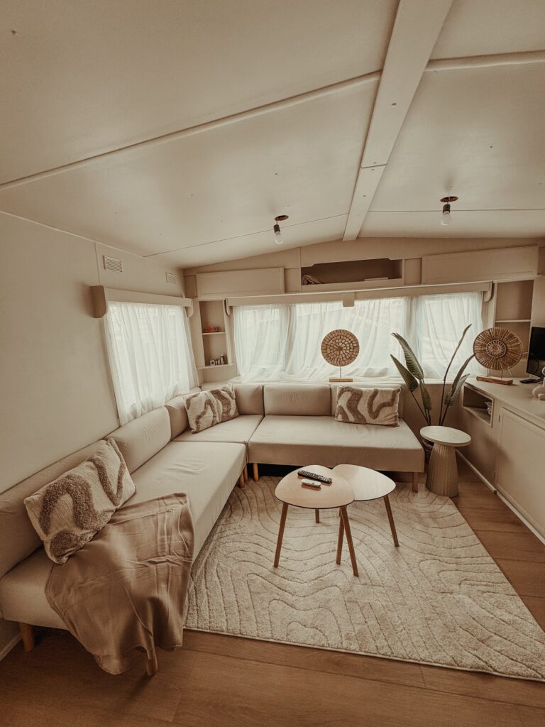 Woonkamer van Slow Nest met zithoek, vloerkleed en rieten wanddecoratie